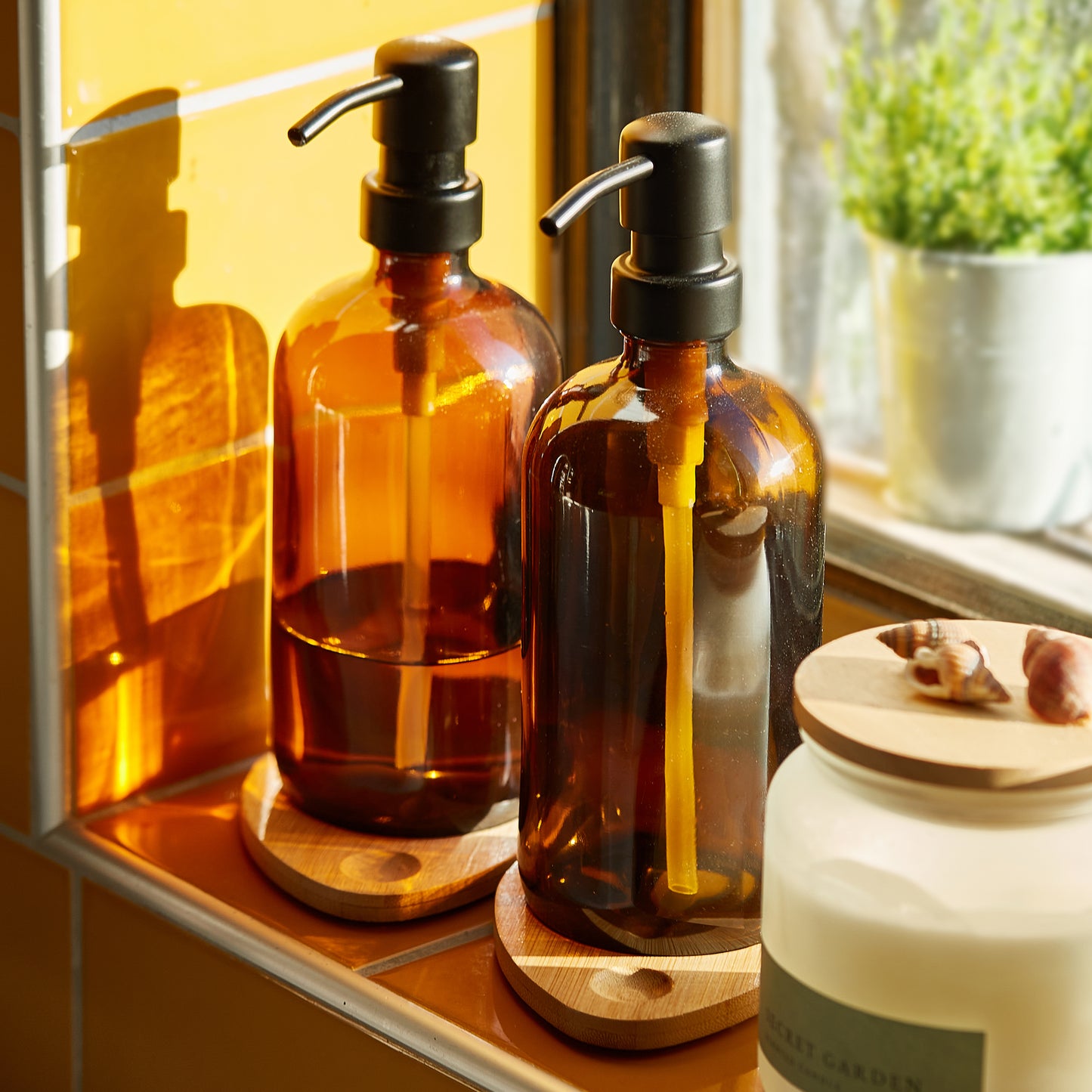 Set of two 500ml refillable amber glass pump bottles with bamboo drip trays