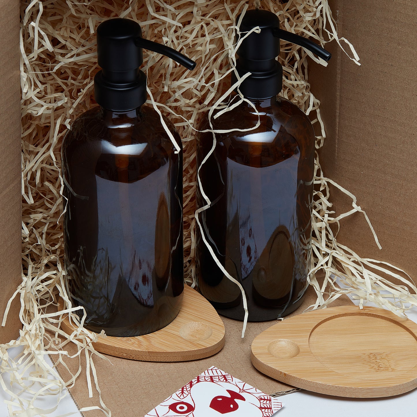 Set of two 500ml refillable amber glass pump bottles with bamboo drip trays